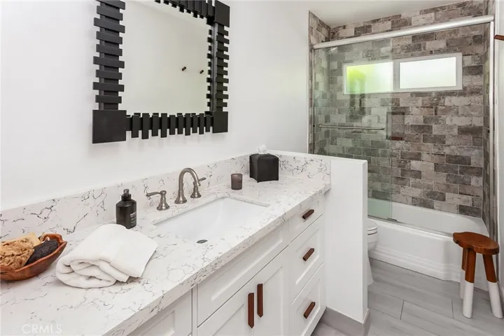 The beautifully finished secondary bath offers a granite topped vanity and a custom tiled tub and shower with a frameless glass enclosure.