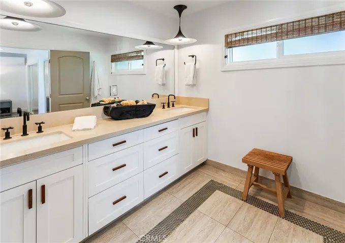 The en suite bath features dual sinks, a quartz topped vanity, designer lighting, tiled flooring, and a glass-enclosed custom walk-in shower.