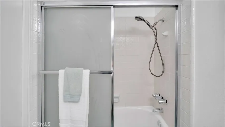 Guest bathroom has a glass enclosed shower and tub.