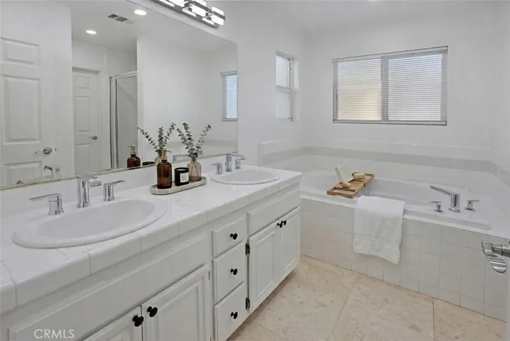 Photo is virtually staged.  Previous photo is how property currently shows. Private primary en suite bath features dual vanities, a jetted soaking tub, separate glass-enclosed shower, and a private water closet.