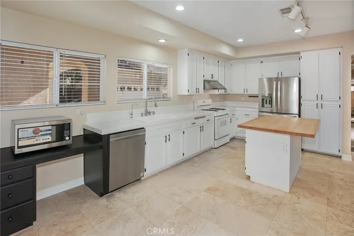 Designed to keep everyone connected, the kitchen blends style with functionality. White cabinetry, a center island with a butcher block countertop, breakfast bar, pantry, gas range, microwave, dishwasher, and a newer French door refrigerator create a space that's ready for everything from busy weekday mornings to entertaining friends.