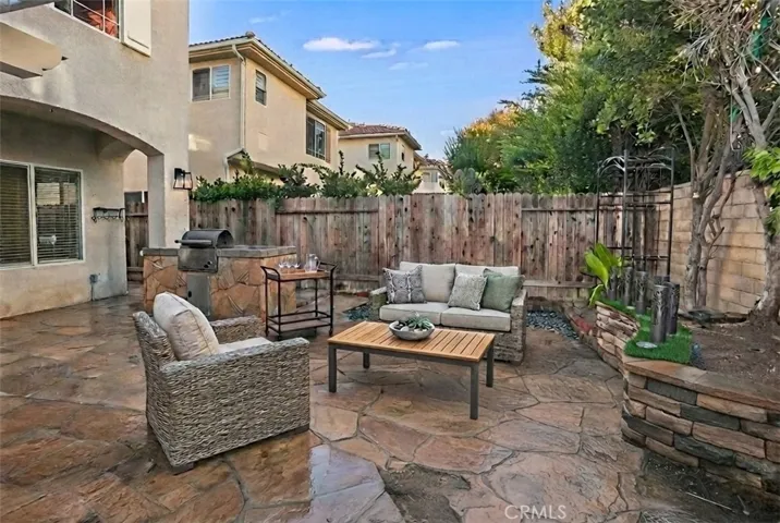 Photo is virtually staged.  Previous photo is how property currently shows. The backyard is designed for easy enjoyment with a pergola-covered stone patio, built-in barbecue, open patio, raised planters, and orange, papaya, and banana trees.