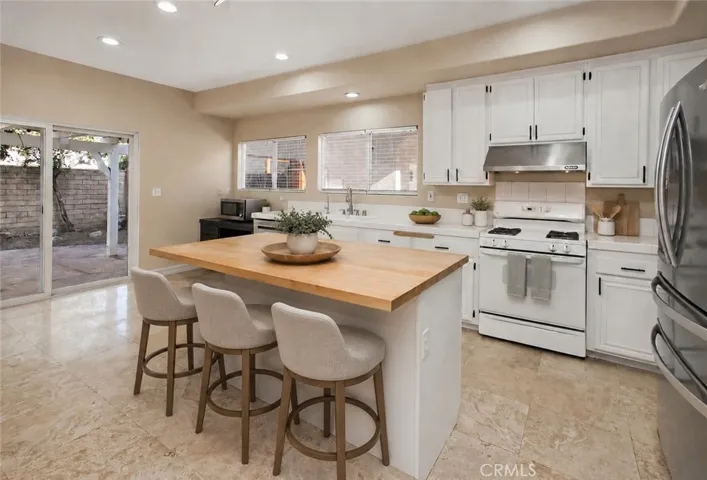 Photo is virtually staged.  Previous photo is how property currently shows. Designed to keep everyone connected, the kitchen blends style with functionality. White cabinetry, a center island with a butcher block countertop, breakfast bar, pantry, gas range, microwave, dishwasher, and a newer French door refrigerator create a space that's ready for everything from busy weekday mornings to entertaining friends.
