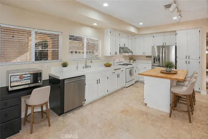 Photo is virtually staged.  Previous photo is how property currently shows. Designed to keep everyone connected, the kitchen blends style with functionality. White cabinetry, a center island with a butcher block countertop, breakfast bar, pantry, gas range, microwave, dishwasher, and a newer French door refrigerator create a space that's ready for everything from busy weekday mornings to entertaining friends.