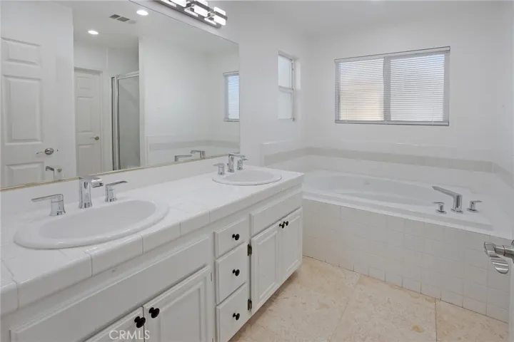 Private primary en suite bath features dual vanities, a jetted soaking tub, separate glass-enclosed shower, and a private water closet.