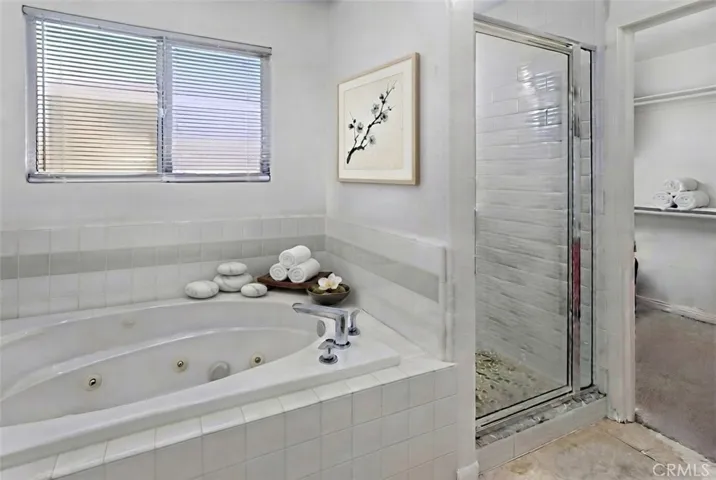 Photo is virtually staged.  Previous photo is how property currently shows. Private primary en suite bath features dual vanities, a jetted soaking tub, separate glass-enclosed shower, and a private water closet.