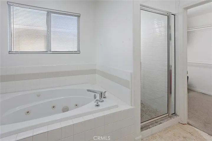 Private primary en suite bath features dual vanities, a jetted soaking tub, separate glass-enclosed shower, and a private water closet.