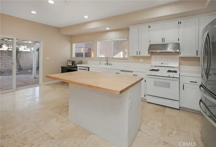 Designed to keep everyone connected, the kitchen blends style with functionality. White cabinetry, a center island with a butcher block countertop, breakfast bar, pantry, gas range, microwave, dishwasher, and a newer French door refrigerator create a space that's ready for everything from busy weekday mornings to entertaining friends.