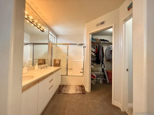 Spacious en suite primary bathroom features double sinks, shower/tub combo, walk-in closet, and separate toilet room.
