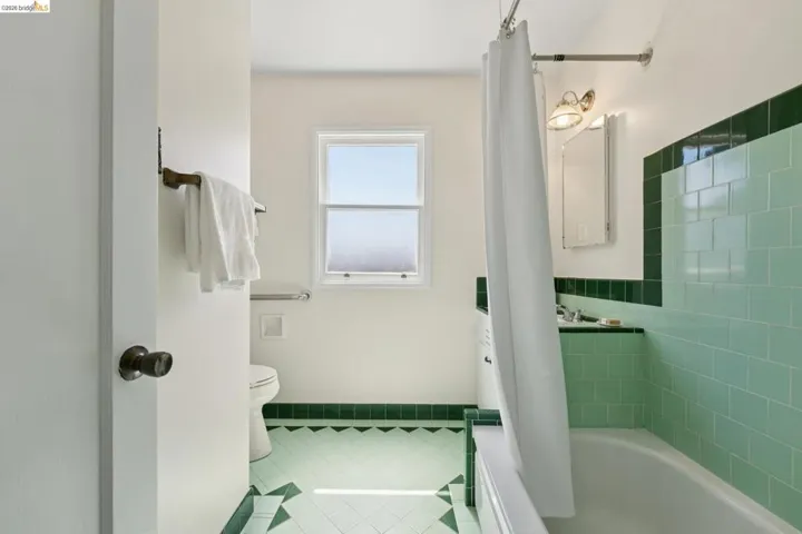 Bathroom featuring light green and dark green tile work, a window, and a built-in bathtub