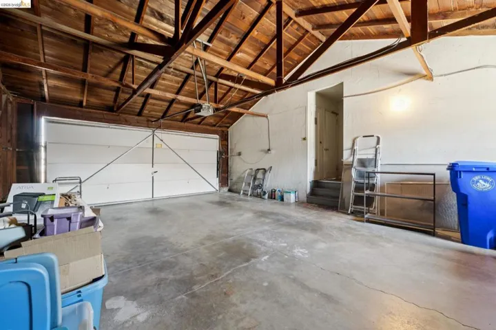 Spacious garage featuring exposed wood beam ceilings and a concrete floor