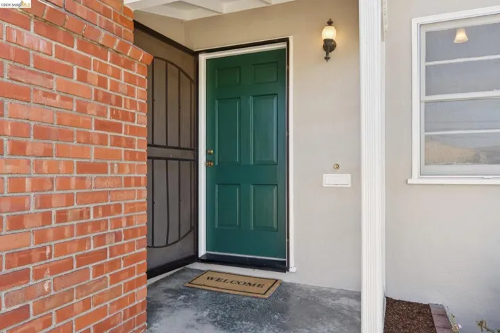 Entryway featuring a panel door, decorative security screen, brick facade, and an exterior wall lantern