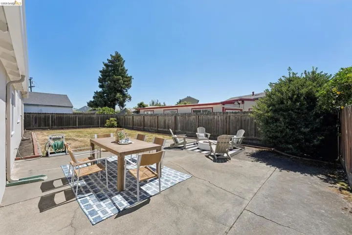Spacious backyard featuring a concrete patio, wood fencing, and a generous grass area