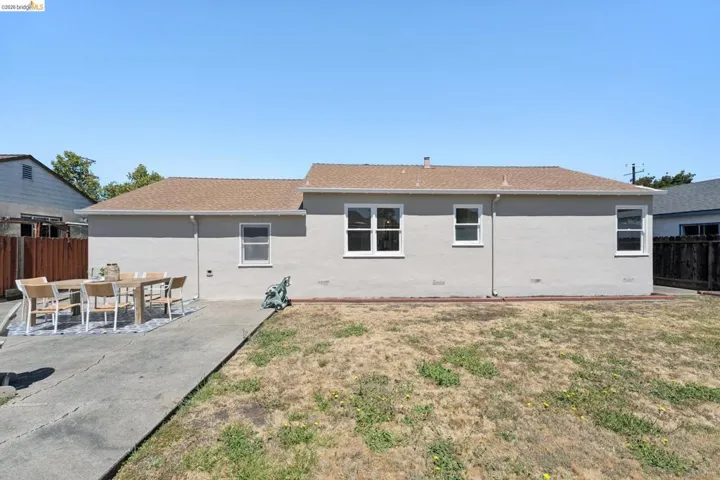 Rear exterior with stucco siding and a brown shingle roof