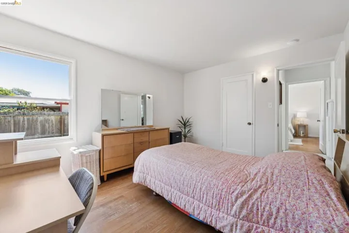 Light-filled room featuring wood-finish flooring, a bright window, and a white paneled door