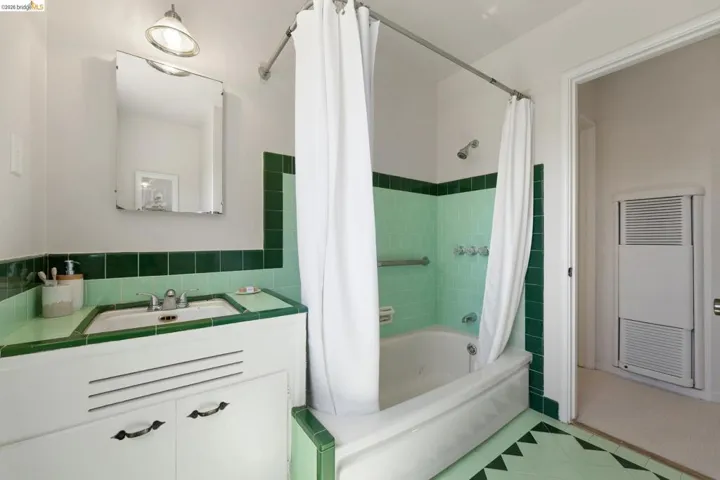 Bathroom featuring a built-in vanity with integrated sink, tiled countertop, and overhead lighting