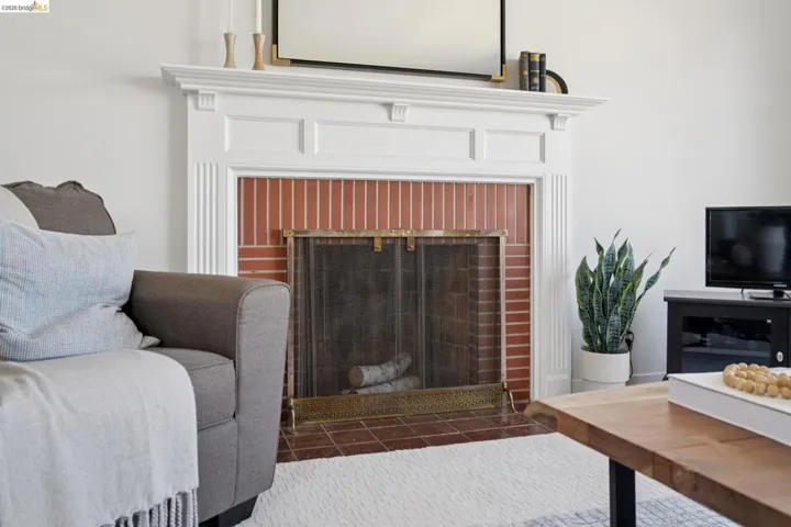 White mantel fireplace with brick surround and brass-toned screen