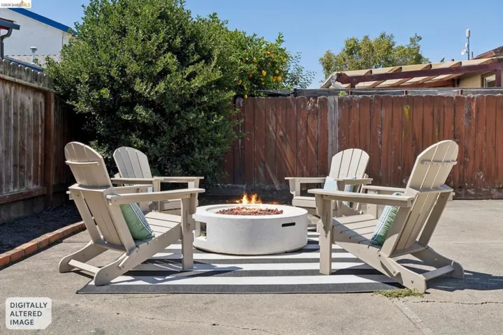 Paved outdoor patio featuring a circular fire pit and perimeter fencing