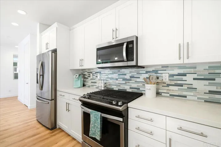 Quartz counters, stainless appliances, and stylish tile backsplash complete the kitchen.