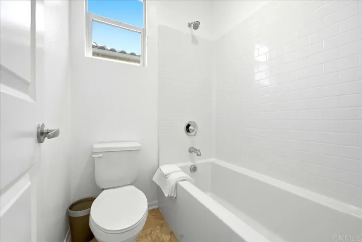 Full bathroom featuring a tub and shower with classic tile surround.