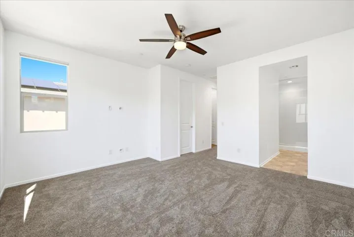 Spacious primary suite with ceiling fan, new carpet, and ensuite bath access.