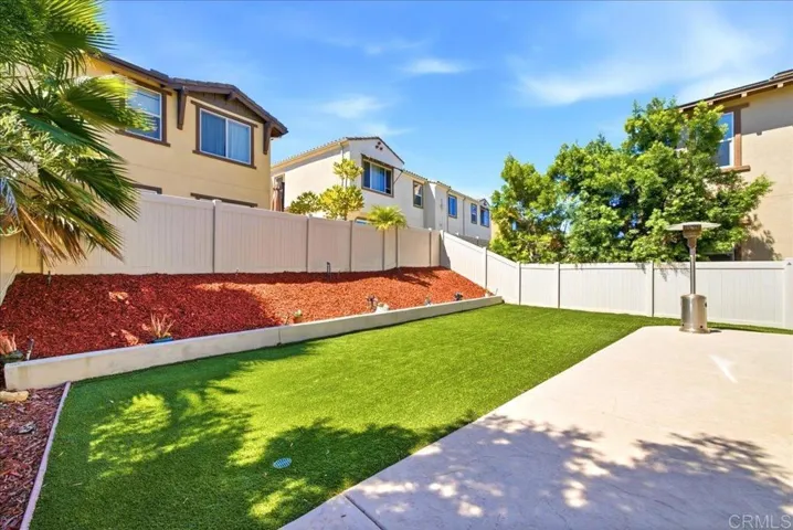 Low-maintenance yard with artificial turf, patio, and landscaped planter beds.