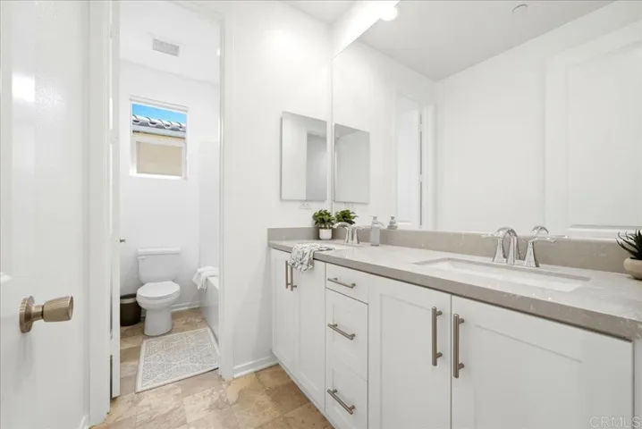 Full bath with quartz vanity and modern cabinetry.