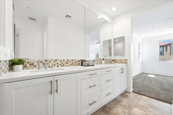 Dual vanity with modern finishes, oversized mirrors, and ample storage.