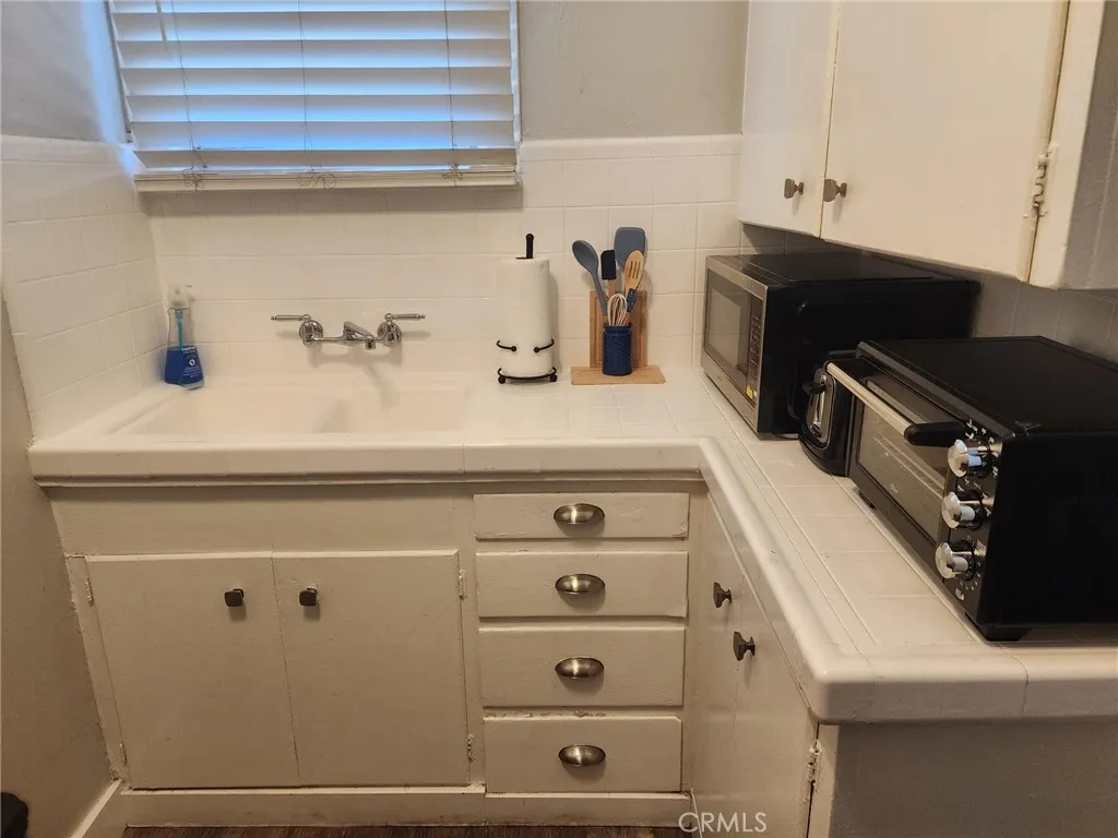 Kitchen with original tile and cupboards to maintain the feel of the 1920's building.
