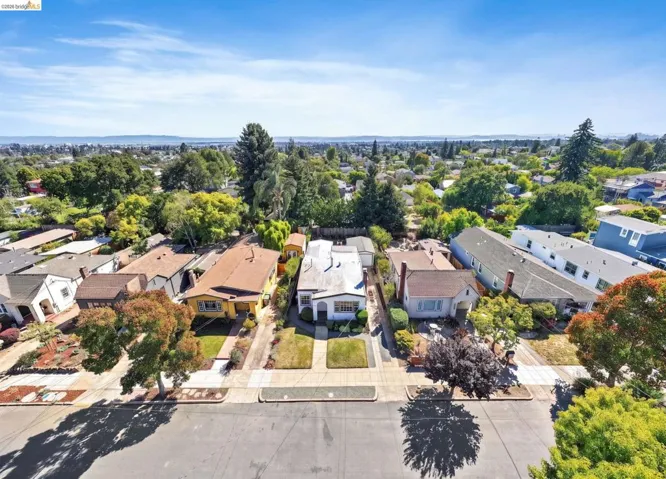 Residential street featuring detached properties with landscaped front yards and mature trees