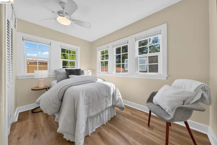 Bedroom featuring wood-finish flooring, a ceiling fan with integrated lighting, and multiple windows providing natural light