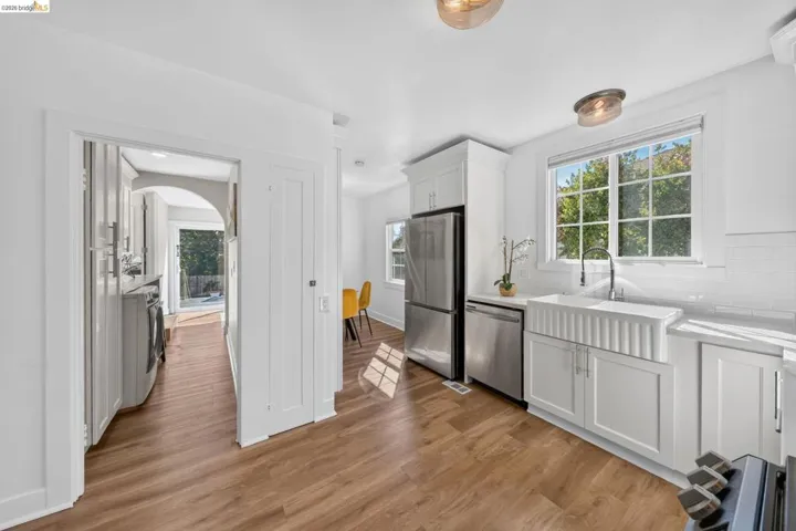 Modern kitchen featuring white shaker cabinetry, stainless steel appliances, a white farmhouse sink with a gooseneck faucet, and white subway tile backsplash