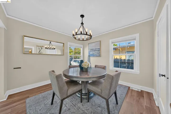 Dining area featuring wood-finish flooring, white baseboards, a contemporary chandelier, and two double-hung windows