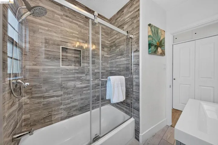 Bathtub and shower combination featuring floor-to-ceiling grey stacked stone tile and a recessed shower niche