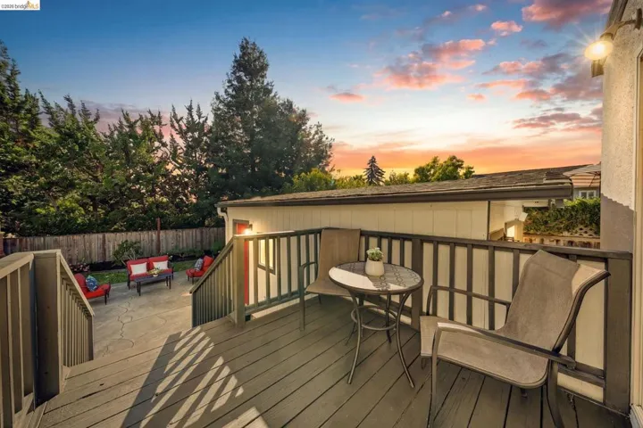 Raised deck with wood-finish flooring and railings, featuring exterior wall-mounted lighting