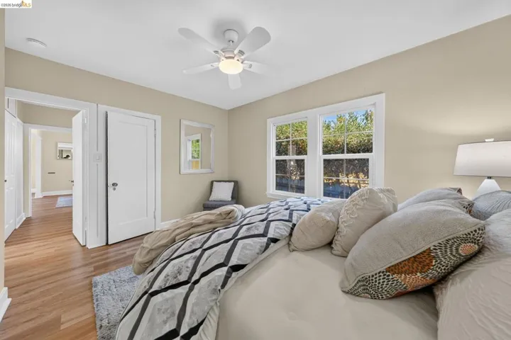 Bedroom featuring wood-finish flooring, a ceiling fan with integrated lighting, and white window trim