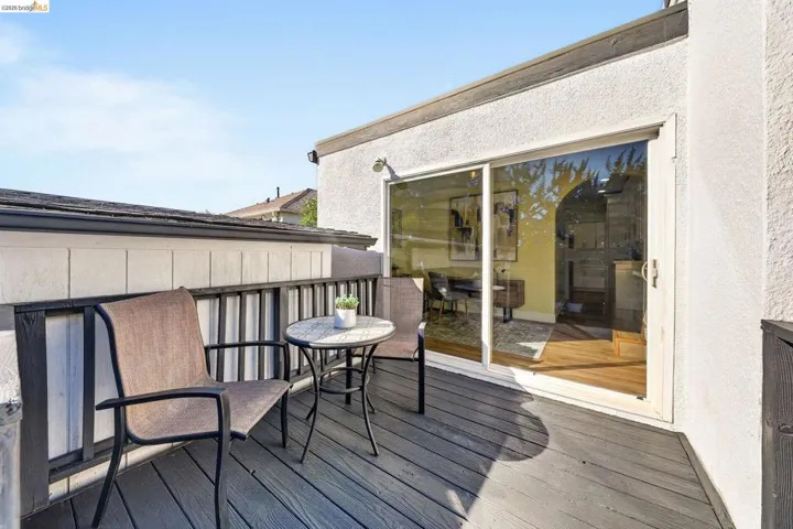 Private exterior deck featuring composite decking, a white stucco exterior wall, and a sliding glass door providing natural light to the interior space