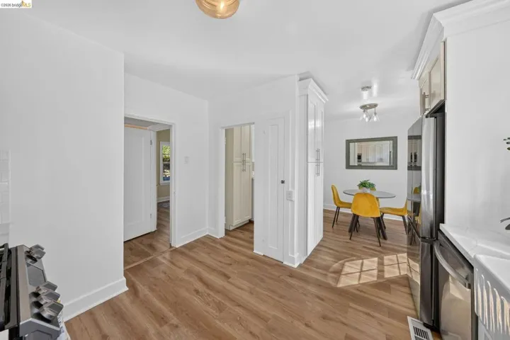 Kitchen area featuring wood-finish flooring, white cabinetry with crown molding, stainless steel refrigerator, and recessed lighting