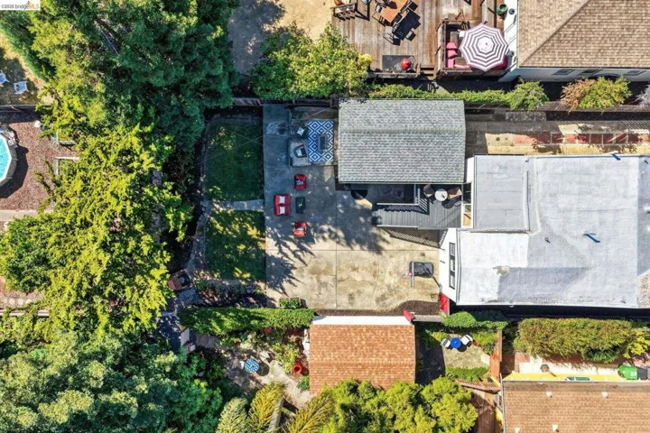 Property featuring a concrete patio, a section of turf, and mature perimeter trees