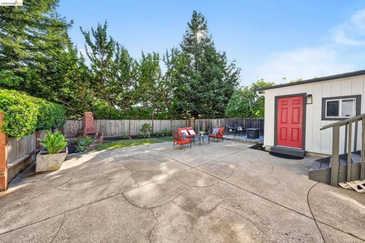 Expansive concrete patio with a decorative pattern, bordered by a wooden fence and mature trees