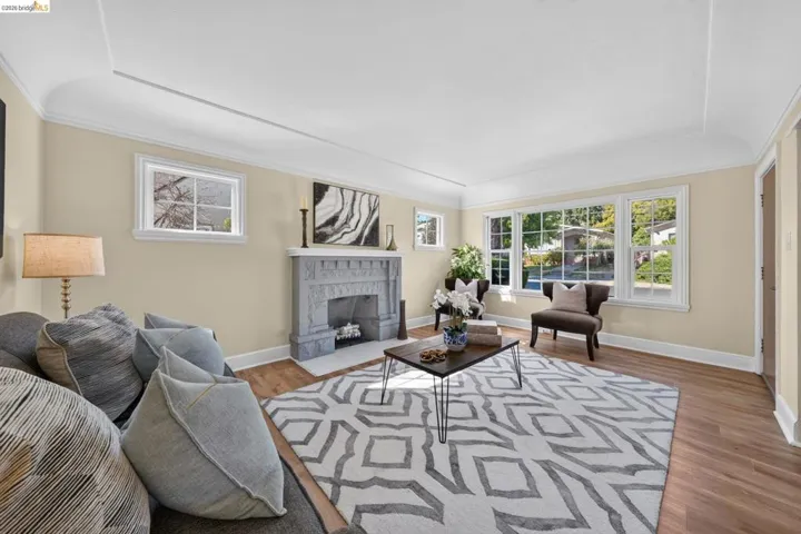 Living room with light-toned walls, wood-finish flooring, and a decorative fireplace