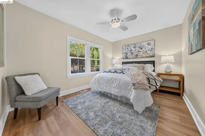 Light-filled room featuring wood-finish flooring, a ceiling fan, and large windows with white trim