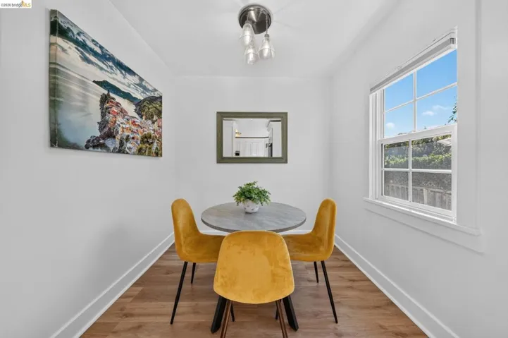 Dining area featuring a large window, wood-finish flooring, white baseboards, and a contemporary ceiling light fixture
