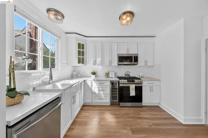 Kitchen featuring white cabinetry, stainless steel appliances, a farmhouse sink, white subway tile backsplash, and wood-finish flooring