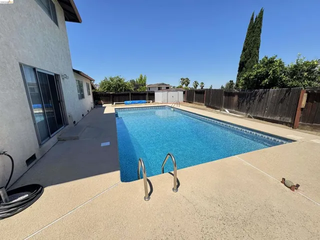 Rectangular swimming pool with a patterned blue liner, surrounded by a concrete deck