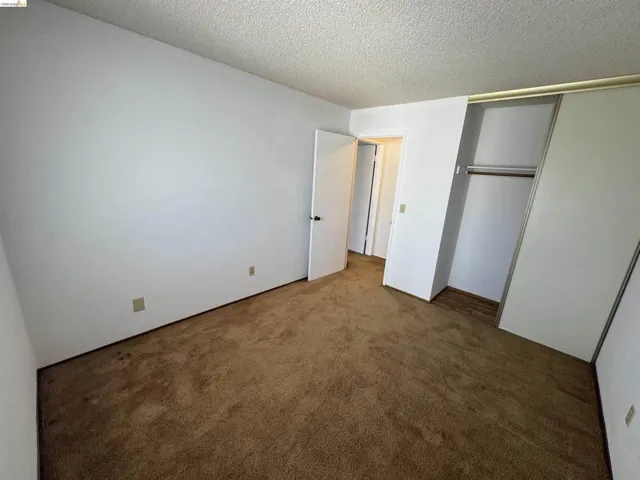 Carpeted interior with white walls and a textured ceiling