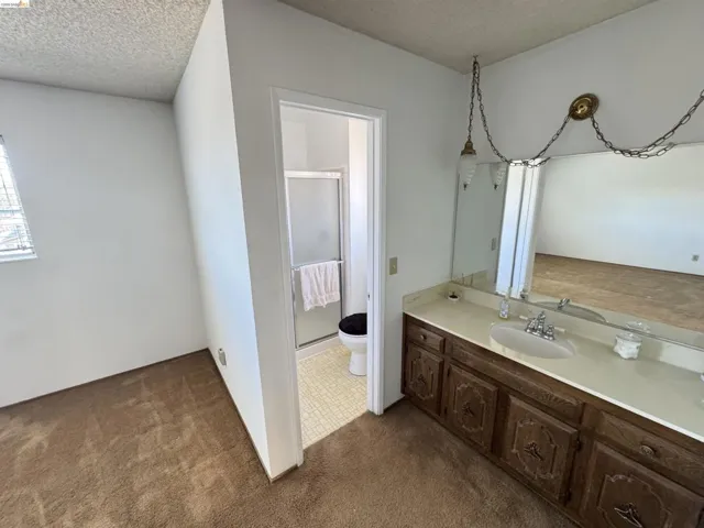 Bathroom vanity featuring a single basin sink, light-toned countertop, and dark wood-finish cabinetry with decorative hardware