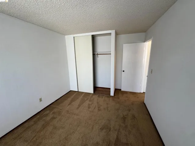 Carpeted interior space featuring white painted walls and a textured ceiling