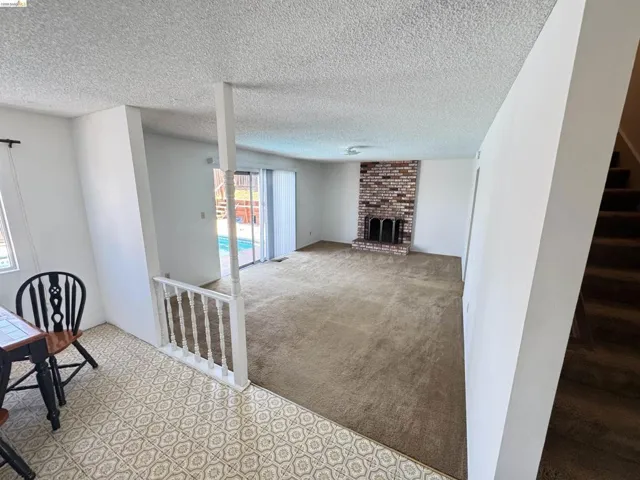 Living room with a brick fireplace and a sliding glass door providing access to the outdoor area with a visible pool