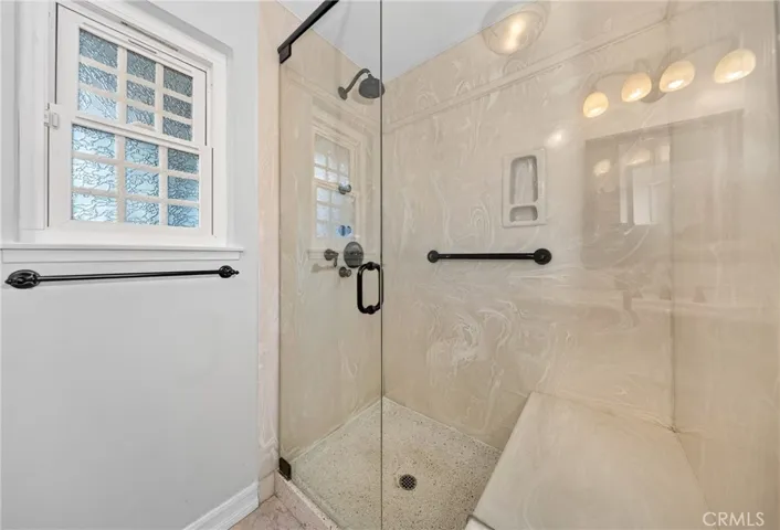 Walk in shower, with seat located in primary bathroom.